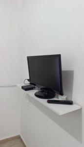 a computer monitor sitting on a white desk at Kit 400mts da praia in Bertioga