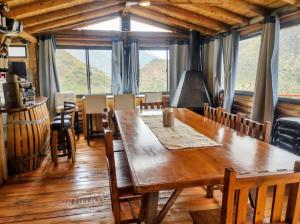 a dining room with a large wooden table and windows at Quincho Cabaña Las Marias in Ciudad Lujan de Cuyo