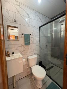 a bathroom with a toilet and a glass shower at Vila do Chaves Casa Seu Madruga 72 in Itajaí