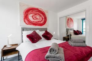 a bedroom with a red and white bed with red pillows at PENTHOUSE - Spacious, Stunning River Views, Foosball Table, Central, River Front, V&A, Train Station, City Centre, Lift Access, Free Parking & Fully Equipped by SUNRISE LONG LETS and SERVICED ACCOMMODATION DUNDEE - Reduced Mobile App Price in Dundee