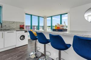 a kitchen with blue chairs at a counter at PENTHOUSE - Spacious, Stunning River Views, Foosball Table, Central, River Front, V&A, Train Station, City Centre, Lift Access, Free Parking & Fully Equipped by SUNRISE LONG LETS and SERVICED ACCOMMODATION DUNDEE - Reduced Mobile App Price in Dundee +59 photos