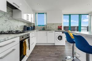 a kitchen with white cabinets and a washer and dryer at PENTHOUSE - Spacious, Stunning River Views, Foosball Table, Central, River Front, V&A, Train Station, City Centre, Lift Access, Free Parking & Fully Equipped by SUNRISE LONG LETS and SERVICED ACCOMMODATION DUNDEE - Reduced Mobile App Price in Dundee