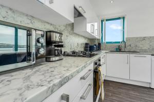 a kitchen with white cabinets and marble counter tops at PENTHOUSE - Spacious, Stunning River Views, Foosball Table, Central, River Front, V&A, Train Station, City Centre, Lift Access, Free Parking & Fully Equipped by SUNRISE LONG LETS and SERVICED ACCOMMODATION DUNDEE - Reduced Mobile App Price in Dundee