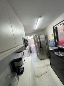 a small kitchen with a refrigerator and a sink at Carnaval 2026 in Tamandaré