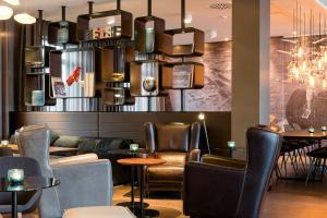 a restaurant with leather chairs and a table andools at Motel One Frankfurt-Airport in Frankfurt