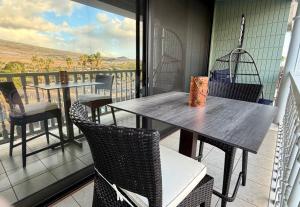 a balcony with two tables and chairs and a view at Compass Blue Lahaina in Lahaina
