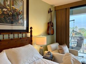 a bedroom with a bed and a guitar on the wall at Compass Blue Lahaina in Lahaina +38 photos