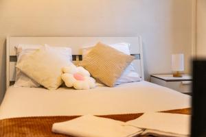 a stuffed teddy bear sitting on a bed with pillows at L'Echo de Saint-Michel - Parking Privé - StyleCosy in Dijon