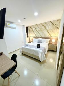 a bedroom with a large white bed and a desk at Hotel Olam Deluxe Valledupar in Valledupar