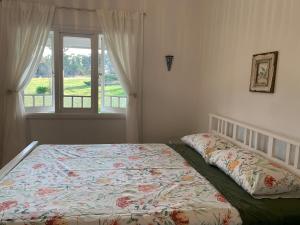 a bedroom with a bed with a floral comforter and a window at Cobargo ButterHaus in Cobargo
