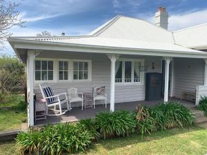 a white house with chairs and a table on a porch at Cobargo ButterHaus in Cobargo