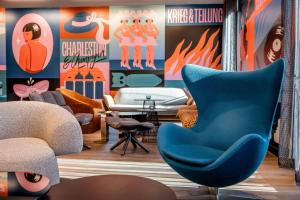 a living room with a blue chair and posters at Motel One Berlin-Potsdamer Platz in Berlin