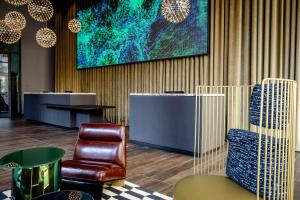 a lobby with chairs and a large painting on the wall at Motel One Berlin-Potsdamer Platz in Berlin