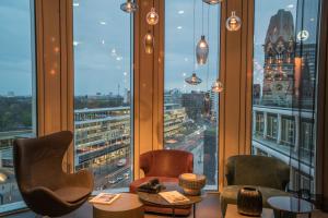 a room with large windows with chairs and tables at Motel One Berlin-Upper West in Berlin +38 photos