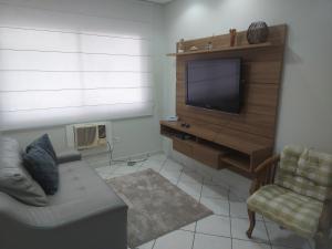 a living room with a couch and a flat screen tv at Recanto da Enseada in Guarujá