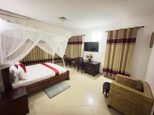 a bedroom with a bed and a chair and a television at Sienna Beach Hotel - Entebbe in Entebbe +48 photos