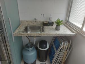 a kitchen counter with a sink and a trash can at Recanto da Enseada in Guarujá +35 photos