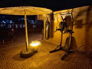 a room with a table with an umbrella and a lamp at Farissi's Zawya Surf House in Aourir