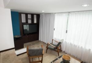 ein Wohnzimmer mit zwei Sesseln und einem Fernseher in der Unterkunft Colombe Hotel Boutique in Xalapa