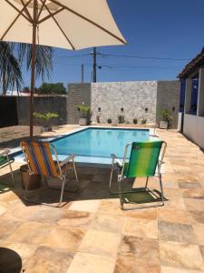 two chairs and an umbrella next to a swimming pool at Casa Estrela do Mar in Conde
