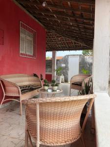a patio with wicker chairs and tables and a red wall at Casa Estrela do Mar in Conde