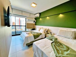 a room with two beds and a green wall at Vacanze - Time in Maceió