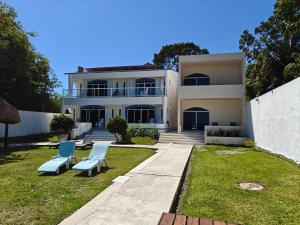 a white house with two blue chairs in the yard at Departamentos blue Turquesa in Bacalar +20 photos