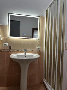 a bathroom with a sink and a mirror and a shower at Bujtina Kenedi in Korçë