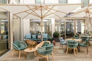 a lobby with chairs and tables and a large umbrella at Motel One Aachen in Aachen