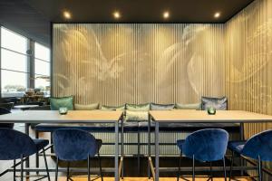 a restaurant with two tables and blue chairs at Motel One Brussels in Brussels