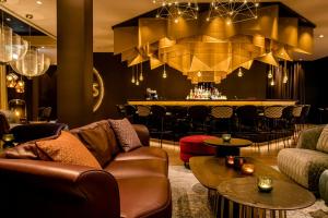a living room with a couch and a bar at Motel One Aachen in Aachen
