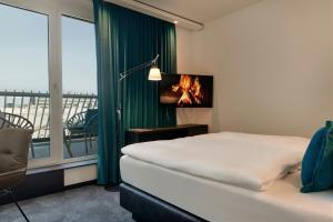 a bedroom with a bed and a tv and a balcony at Motel One Aachen in Aachen