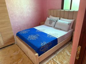 a small bedroom with a bed with blue sheets and pillows at Small beautiful villa in Al Massira Airport