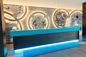 a counter in a room with a wall with paintings at Motel One München-Olympia Gate in Munich
