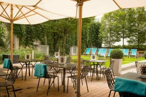a patio with tables and chairs under an umbrella at Motel One München-Sendlinger Tor in Munich