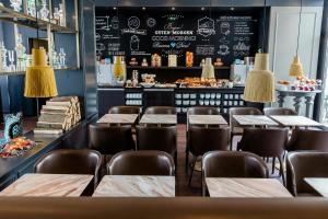 a restaurant with tables and chairs and a chalkboard at Motel One München-Sendlinger Tor in Munich
