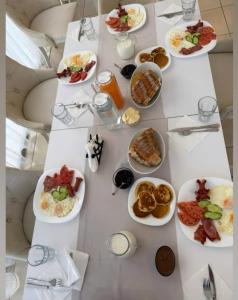 a white table with plates of food on it at Hotel Amaiià in Sarandë