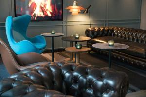a living room with a couch and a chair and tables at Motel One Lübeck in Lübeck