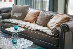 a brown leather couch with pillows and a table at Motel One Lübeck in Lübeck