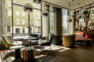a living room with chairs and tables and large windows at Motel One Köln-Mediapark in Cologne