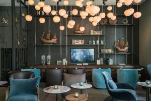 a restaurant with blue chairs and tables and a television at Motel One Lübeck in Lübeck +24 photos