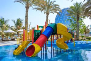 eine Wasserrutsche in einem Pool mit Palmen in der Unterkunft Al Raha Beach Hotel in Abu Dhabi