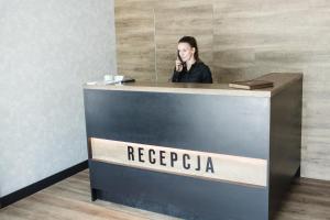 a woman talking on a phone at a reception desk at Hotel Browar Wiatr in Uniejow