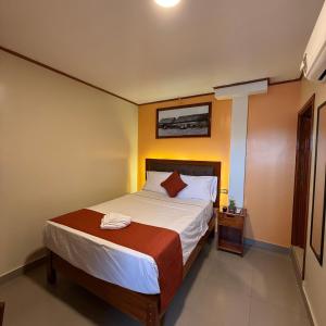 a small bedroom with a bed with white sheets at Hotel Yagua Iquitos in Iquitos