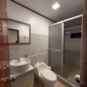 a bathroom with a toilet and a sink and a shower at Hotel Yagua Iquitos in Iquitos