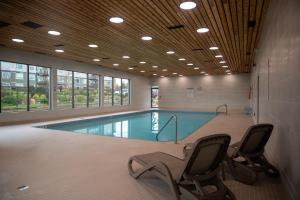 a swimming pool with two chairs in a building at Bayside Resort, an Ascend Collection Resort in Parksville