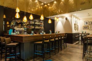 a bar with a bunch of stools in a restaurant at Motel One Leipzig-Augustusplatz in Leipzig