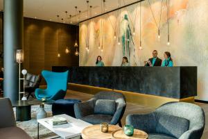 a lobby with chairs and a counter with a mirror at Motel One Köln-Neumarkt in Cologne