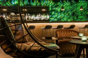 a bar with chairs and a green wall at Motel One Freiburg in Freiburg im Breisgau