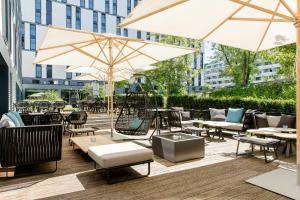 a patio with tables and chairs and umbrellas at Motel One München-Deutsches Museum in Munich